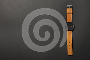 Stylish wrist watch on dark background, top view with space for text.