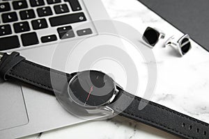 Stylish wrist watch and laptop on marble table.