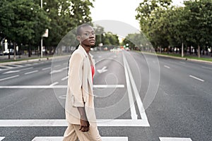 Stylish young adult woman looking at camera crossing the street in the city