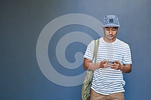 Stylish young Asian man reading a text message outside