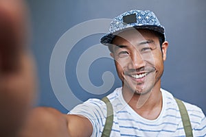 Stylish young Asian man taking a selfie outside