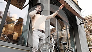 Stylish young bearded man with bicycle answering phone call