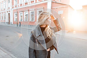 Stylish young beautiful girl in a fashionable gray jacket posing