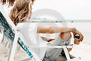 Stylish young beautiful woman in casual wear relaxing in chair o