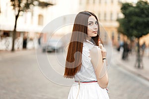Stylish young beautiful woman in white dress on the street.
