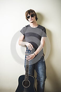 Stylish young blonde hipster man playing guitar