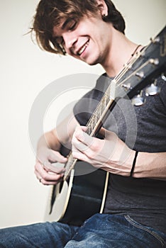 Stylish young blonde hipster man playing guitar