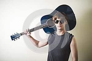 Stylish young blonde hipster man playing guitar