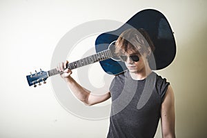 Stylish young blonde hipster man playing guitar