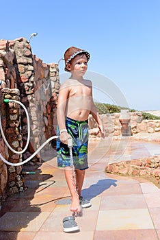 Stylish young boy rinsing off his feet