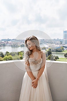 Stylish young bride in classical wedding dress posing with a bridal bouquet outdoors. Female model in luxurious wedding