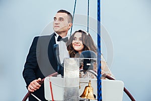 Stylish young bride and groom huging and kissing on board the yacht