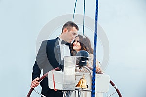 Stylish young bride and groom huging and kissing on board the yacht