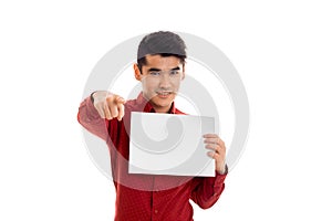 Stylish young brunette male model in red t-shirt posing with empty placard in his hands smiling on camera isolated on