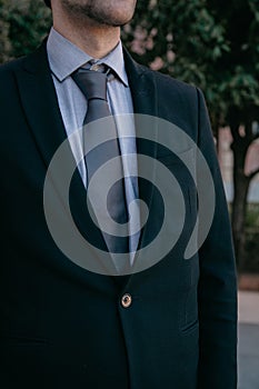 Stylish young business man wearing  a suit and tie confidently standing with trees in the background