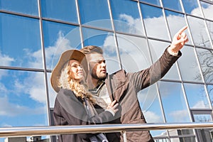 stylish young couple in autumn outfit pointing away