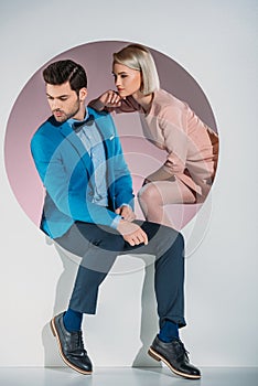 stylish young couple looking away while sitting together in aperture