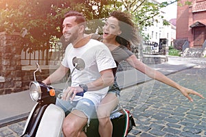 Stylish young couple sits a scooter in the street.