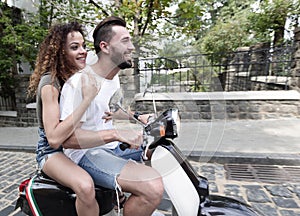 Stylish young couple sits a scooter in the street.