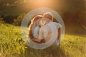 Stylish young couple sitting on a hill and admiring the sunset. A film photo with a light and a sunlight, a