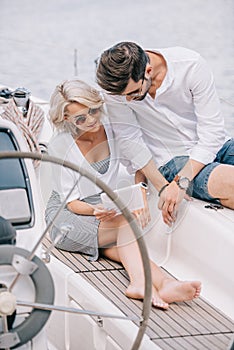 stylish young couple in sunglasses using digital tablet