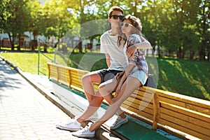 Stylish young couple teenagers sitting on the bench city, summer day