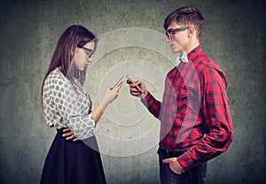 Couple using smartphones totally absorbed in online life, not talking to each other, facing one another.