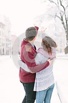 Stylish young couple walking on european winter streets , have fun and hugging. Wearing trendy season outfit. Creamy