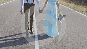 Stylish young couple walking by the hand on the road among the mountains