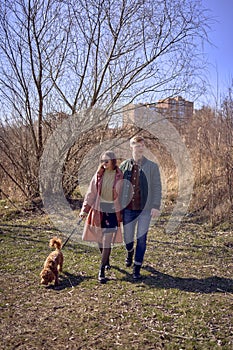 a stylish young couple walking with their dog in nature