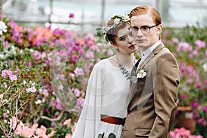 stylish young elegant wedding couple standing together between flowers