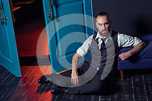 Stylish young fashion model in a suit near door with red light. Business style. Fashionable image.