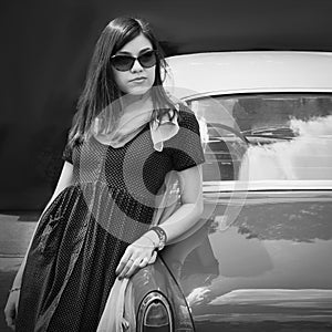 Stylish, young girl on a background of retro cars. Black and white photo. Travels. Auto transport