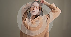 Stylish young girl dancing quickly moving gesturing in camera in studio. Contemporary dance, hip hop and rap performance