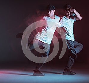 Stylish young guy breakdancer dancing hip-hop in neon light. Dance school poster. Long exposure shot