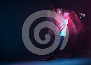 Stylish young guy breakdancer dancing hip-hop in neon light. Dance school poster. Long exposure shot