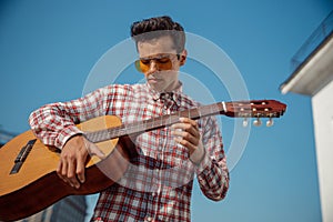 Stylish young guy holding a guitar outdoors