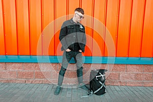 Stylish young guy with sunglasses in trendy black denim clothing