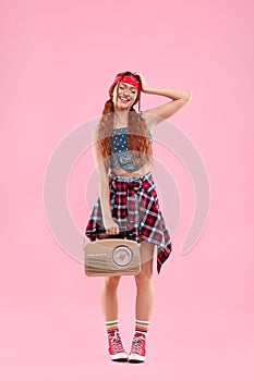 Stylish young hippie woman with retro radio receiver on pink background