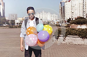 Stylish young man with balloons on the city street