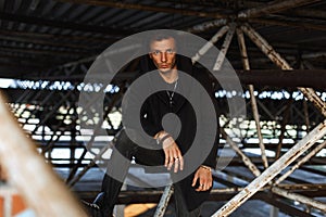 Stylish young man in a hood in black robes is posing