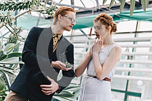 stylish young man with jewelry box making proposal to beautiful surprised girl