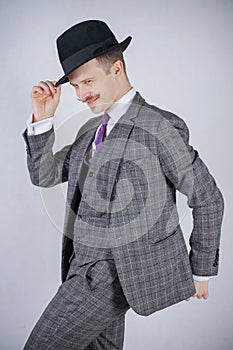 Stylish young man in plaid retro business suit and vintage top hat on white solid background in Studio