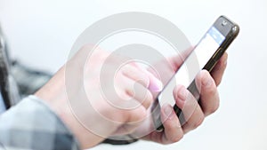 Stylish young man in a plaid shirt uses a smartphone