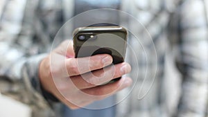 Stylish young man in a plaid shirt uses a smartphone