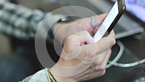 Stylish young man in a plaid shirt uses a smartphone