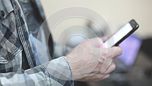 Stylish young man in a plaid shirt uses a smartphone