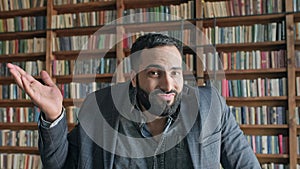 Stylish Young Man Scratching The Back Of His Head In The Library.