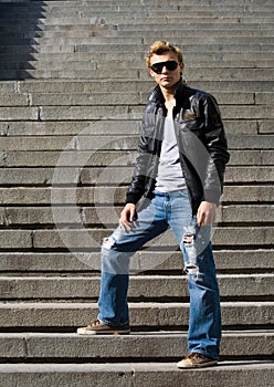 Stylish young man stands on the stair