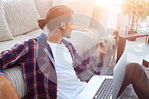 Stylish young man stroking his pet and working on laptop